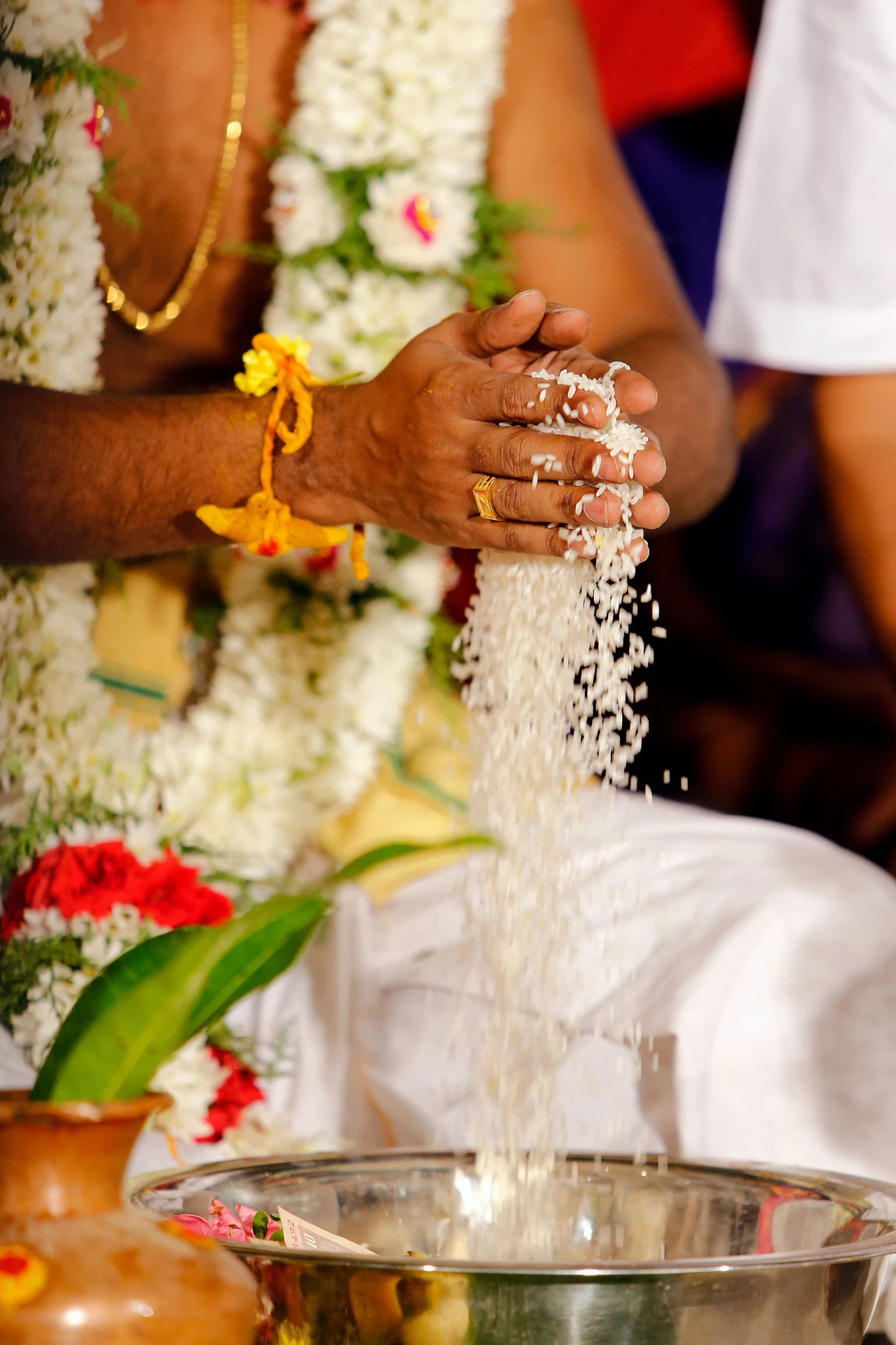 Hands sharing rice as part of a wedding ritual